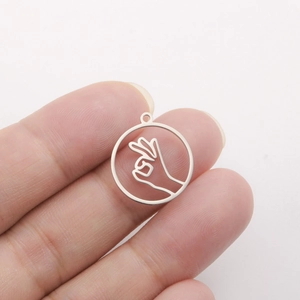 Detail of a 18K gold plated heart gesture pendant showing its compact size on a finger