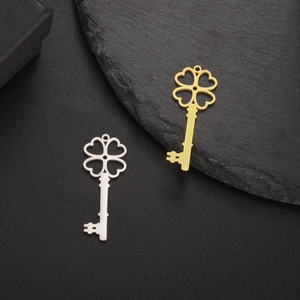 Pendentifs clé trèfle en acier inoxydable doré et argenté sur fond noir texturé