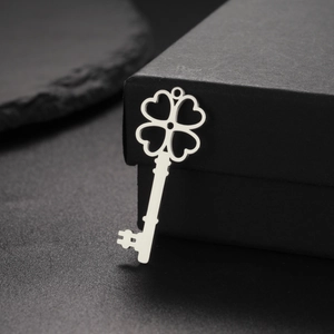 Vue macro d'un pendentif clé cœur à trèfle en acier inoxydable sur une base en pierre noire