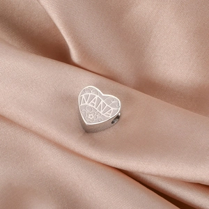 Détail macro du pendentif cœur argenté avec gravure NANA et motif floral