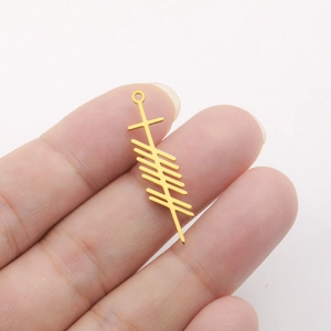 Close-up of golden stainless steel pendant with Ogham rune design on a white background