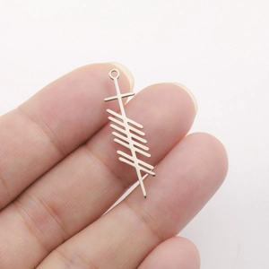 Close-up of a stainless steel Ogham alphabet pendant showing texture and scale on fingers
