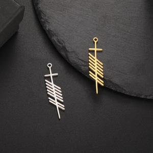Detailed view of silver and gold Ogham-inspired stainless steel pendants on black slate