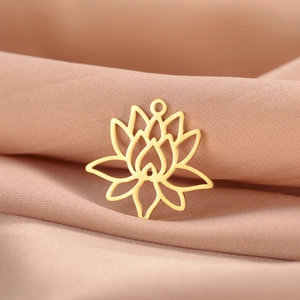 Pendentif lotus ajouré en acier doré posé sur un tissu élégant en soie rose