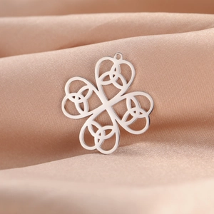 Macro shot of silver stainless steel four-leaf clover pendant with Celtic knot on satin