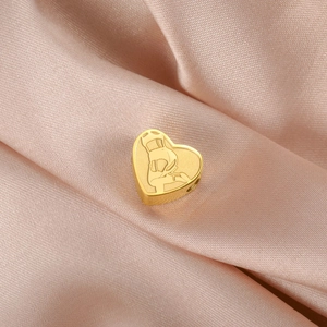Gros plan d'un pendentif coeur doré avec relief sur un fond en tissu satiné rose
