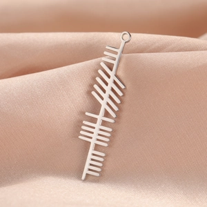 Macro detail of silver stainless steel Ogham tree alphabet pendant on champagne satin cloth