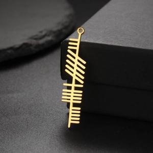 Macro shot of gold Ogham alphabet rectangular pendant with top ring on black slate