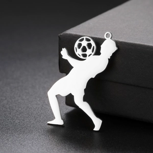 Vue macro d'un pendentif de footballeur en acier argenté sur boîte à bijoux noire