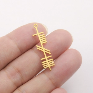 Detailed close-up of a golden stainless steel Ogham symbol pendant held by hand