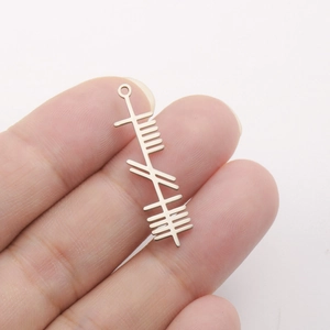 Macro detail of silver Celtic tree pendant charm held by hand for scale and texture