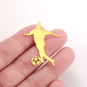 Close-up of golden soccer player pendant held in hand showing size and metal finish