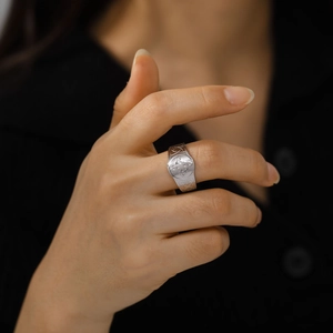 Makroaufnahme eines breiten Stahlrings mit keltischem Knoten am Finger des Models
