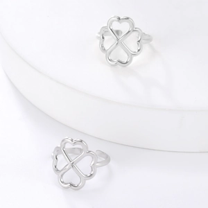 Macro shot of silver adjustable clover rings with heart-shaped cutouts on white podium
