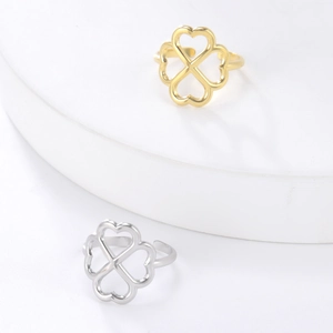 Golden and silver four-leaf clover adjustable rings on white minimalist stand