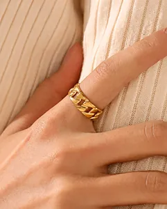 Close-up of golden Cuban link stainless steel ring on model finger with knit sweater