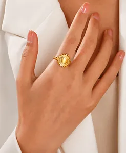 Gros plan d'une bague médaille cœur plaquée or 18 carats avec anneau torsadé sur main