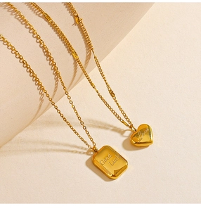 Dettaglio di collane in oro acciaio inossidabile con ciondolo a cuore Love e quadro Good Luck