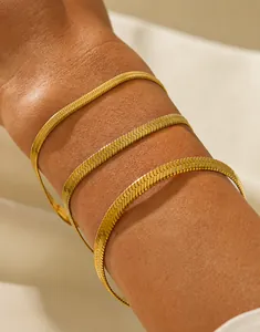 Dettaglio di tre bracciali a catena piatta a serpente in acciaio inossidabile oro