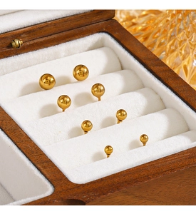 Polished gold ball stud earrings in various sizes displayed on white velvet padding