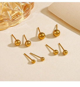 Macro detail of three sizes of gold ball stud earrings with polished mirror finish