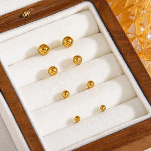 Set of four pairs of gold round ball stud earrings in varying sizes on white velvet