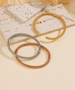Dettaglio di tre bracciali a sfere nelle finiture oro, argento e oro rosa lucido