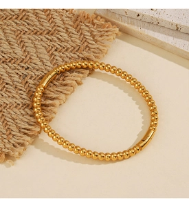Dettaglio del bracciale a sfere dorate in acciaio inossidabile su juta e base di pietra