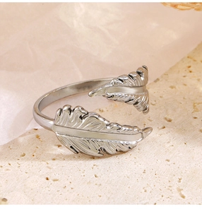 Detalle de anillo de plumas plateado con texturas intrincadas de metal cepillado