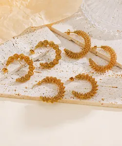 Macro-opname van gouden C-vormige oorringen met fijne gewikkelde metaaldraadtextuur