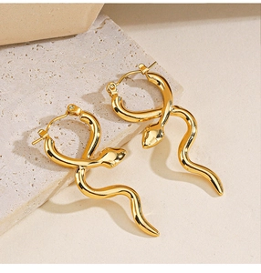 Detail shot of golden snake hoop earrings on a minimalist beige stone texture