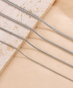 Detalle de cuatro cadenas de serpiente de acero inoxidable de varios grosores sobre piedra