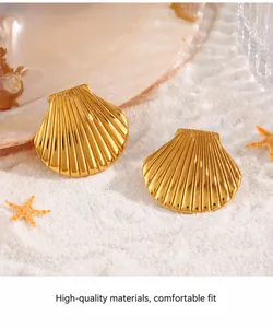 Detailopname van gouden schelpoorringen met stralende textuur op wit strandzand