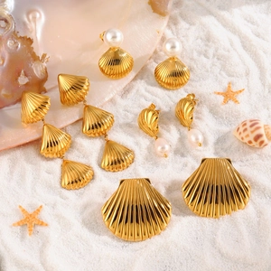 Gouden schelpoorbellen met parels op wit strandzand voor een zomerse vakantie uitstraling