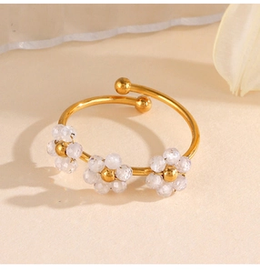 Détail d'un bracelet ouvert doré orné de trois délicates fleurs en perles de zircon