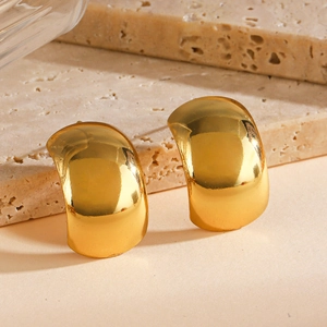 Polished gold minimalist geometric hoop earrings displayed on beige travertine stone