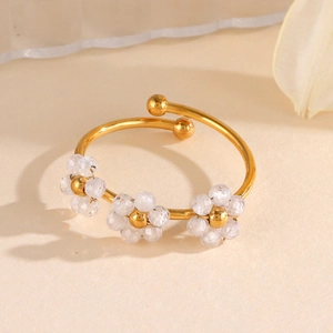 Bracelet jonc ouvert doré minimaliste avec fleurs en zircon sur fond beige neutre