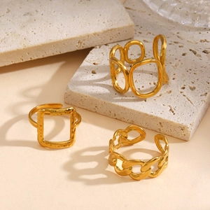 Tres anillos dorados con patrón de martillo y diseño de cadena sobre piedra