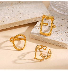 Detailed view of gold geometric rings with lava texture and heart patterns on stone base