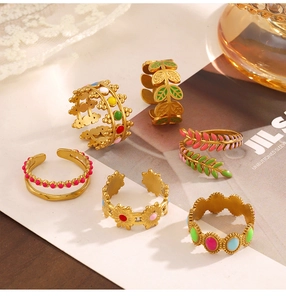 Macro detail of gold stainless steel rings with colorful enamel floral and leaf patterns