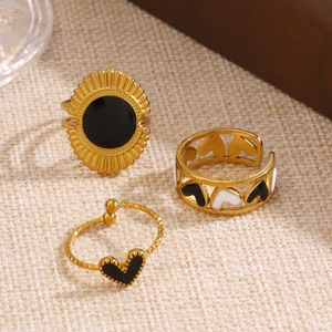 Lot de trois bagues en acier doré avec émail noir à motifs de cœur et de fleurs