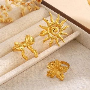 Drei goldene klobige offene Ringe mit Sonnen-, Schmetterlings- und Blumendesign auf Samt