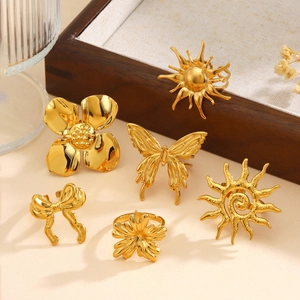 Goldenes Titanstahl-Ring-Set mit Blumen-, Schmetterlings- und Sonnenmotiven auf Holztablett