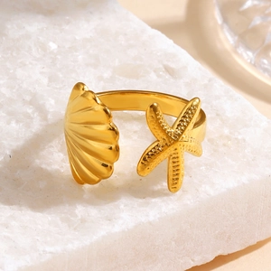 Minimalist gold starfish and seashell open ring on a textured white stone setting