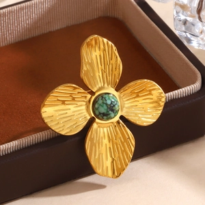 Bague fleur dorée avec pierre verte et pétales texturés sur une boîte à bijoux