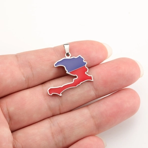 Detail of Haiti map pendant held in hand showing dual-tone red blue enamel finish