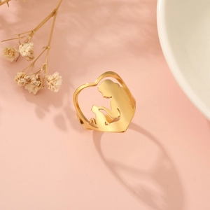 Macro shot of 18K gold heart-shaped ring with a cat silhouette against light pink background