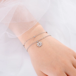Détail d'un bracelet double couche en acier inoxydable avec marguerite et perles argentées