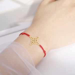 Rode gevlochten touwarmband met een gouden geometrische hanger om de pols van een model