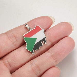 Sudan map pendant with 18K gold plating and enamel flag colors held in hand